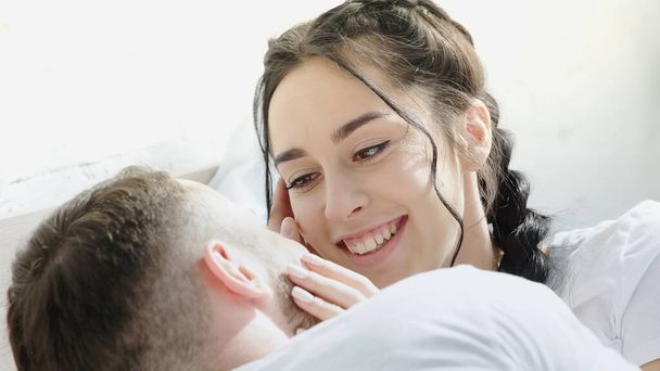 pleased brunette woman touching face of boyfriend at home  - Zdjęcie, obraz