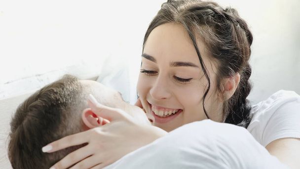 веселая брюнетка женщина трогает лицо своего парня дома  - Фото, изображение