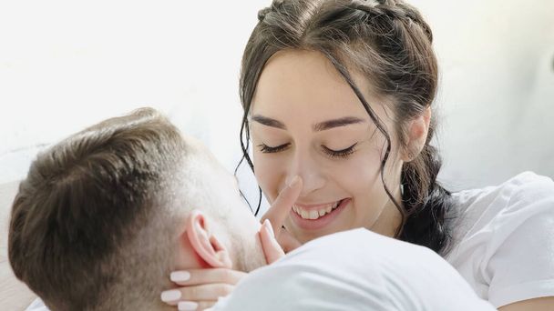 boyfriend touching nose of cheerful brunette woman with braids  - Valokuva, kuva