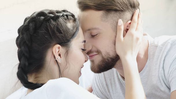 mulher feliz abraçando namorado barbudo com olhos fechados em casa - Foto, Imagem