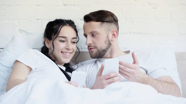 bearded man and happy woman holding cellphones at home  - Foto, imagen