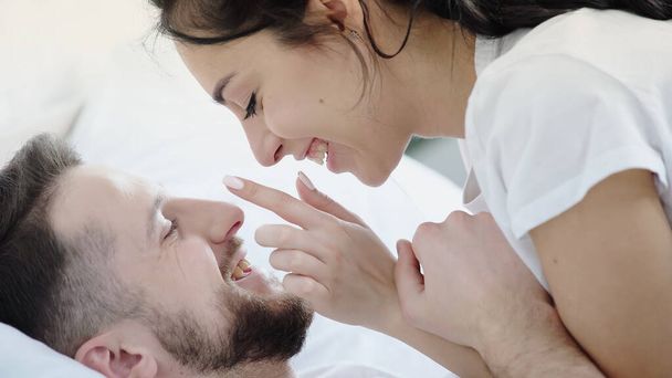 cheerful woman touching face of happy bearded boyfriend  - Fotografie, Obrázek