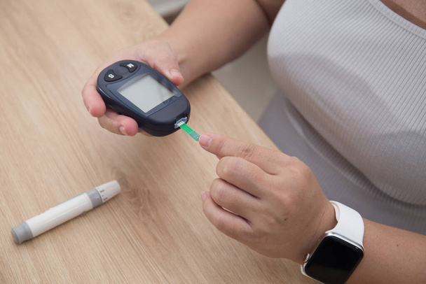 Close-up van de handen van de vrouw controleren bloedsuikerspiegel door Glucose meter met behulp van als Medicijn, diabetes, glycemische, gezondheidszorg en mensen concept. - Foto, afbeelding