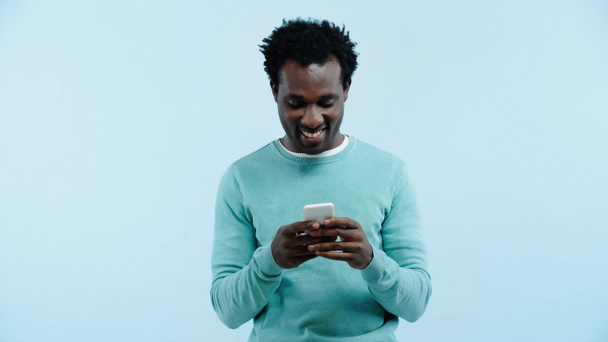 smiling african american man messaging on cellphone isolated on blue - Фото, зображення
