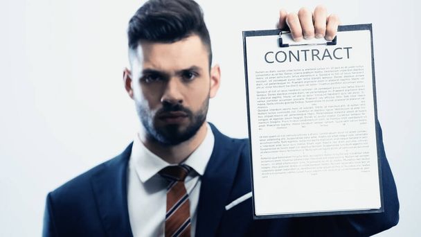 blurred businessman looking at camera while showing contract isolated on white - Fotó, kép