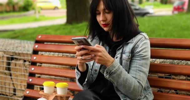 Femme assise sur le banc dans le parc avec à emporter nourriture et café - Séquence, vidéo