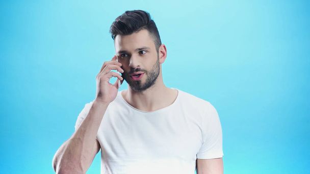 concentrated man talking on mobile phone isolated on blue - Фото, изображение