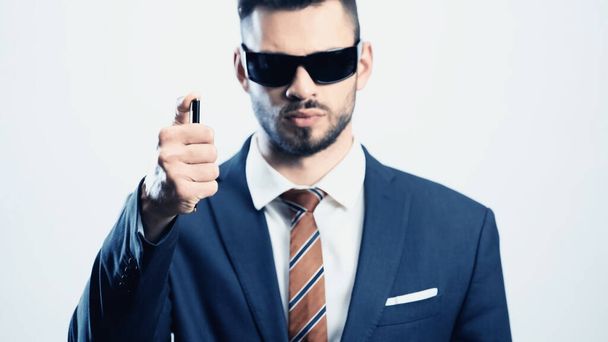 размытый бизнесмен в темных солнцезащитных очках, держащий ручку изолированной на белом - Фото, изображение