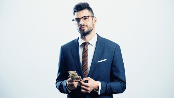 уверенный бизнесмен смотрит в камеру, держа доллары изолированными на белом - Фото, изображение
