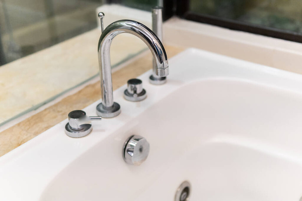 L'eau claire coule du robinet brillant dans l'évier dans la salle de bain, vue rapprochée. Système d'eau dans le concept immobilier résidentiel. - Photo, image
