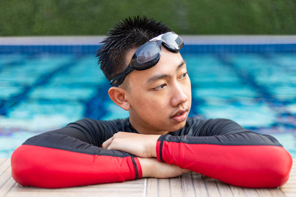 Sport és rekreációs koncepció egy férfi fiatal pihenő úszás gyakorlattal gazdaság és pózol a szélén az uszoda. - Fotó, kép
