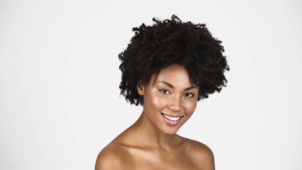 Африканська американка з ідеальною шкірою посміхається перед камерою, ізольованою на сірому  - Фото, зображення