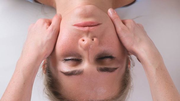 Massaggio di mento di donna giovane donna durante massaggio di faccia a salone di bellezza - Foto, immagini