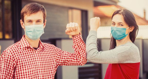 Gomito a gomito. Amici in maschera protettiva medica sul viso salutano i gomiti in quarantena - Foto, immagini