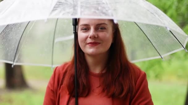 Yağmurlu bir günde elinde şeffaf şemsiye tutan güzel bir kadın. Yağmur damlaları - Video, Çekim
