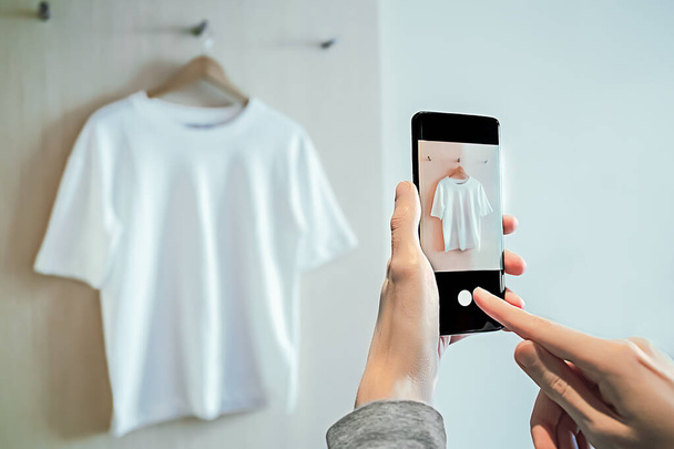 Mann fotografiert auf Smartphone gebrauchte Kleidung zum Weiterverkauf - Foto, Bild