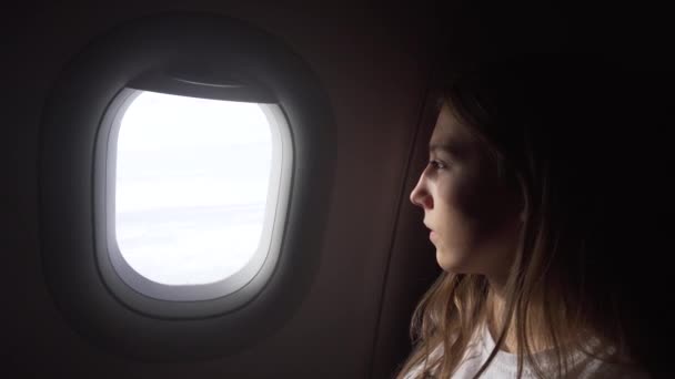 Κορίτσι που κάθεται δίπλα στο παράθυρο του αεροσκάφους και κοιτάζει έξω. - Πλάνα, βίντεο