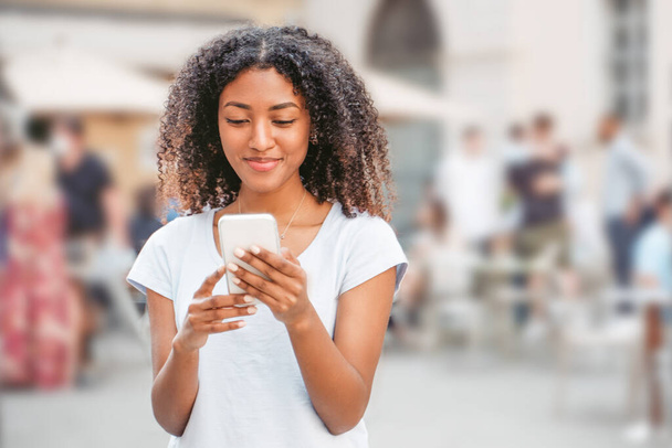 Portrait of black girl using cell phone in city street - Фото, зображення