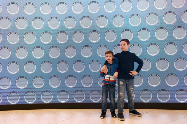Two children on background of glowing wall panel in shopping center  - Photo, image