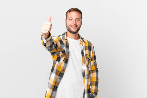 handsome blonde man feeling proud,smiling positively with thumbs up - Foto, Bild