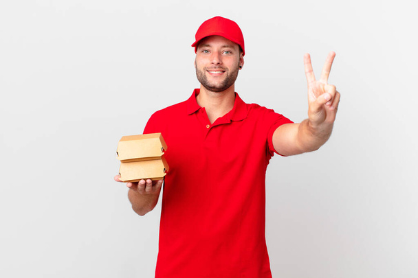 burger deliver man smiling and looking friendly, showing number two - Foto, immagini