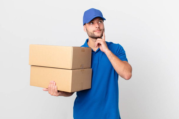 package deliver man smiling happily and daydreaming or doubting - Fotoğraf, Görsel