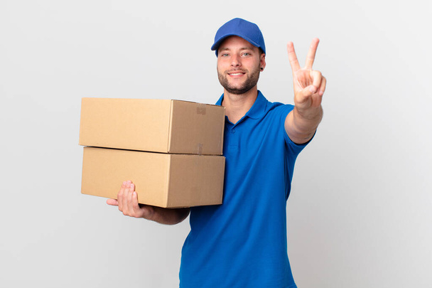 package deliver man smiling and looking happy, gesturing victory or peace - Photo, Image