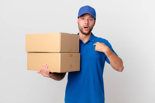 package deliver man looking shocked and surprised with mouth wide open, pointing to self - Φωτογραφία, εικόνα