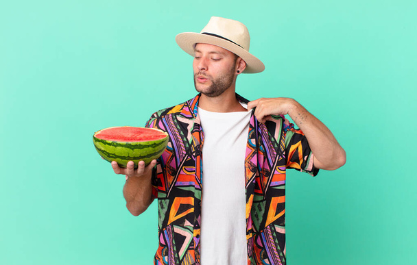 handsome traveler man feeling stressed, anxious, tired and frustrated and holding a watermelon. holidays concept - Valokuva, kuva