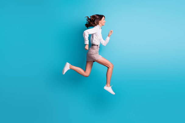 Full size profile photo of brunette girl jump run wear shirt skirt sneakers isolated on teal background - Photo, image