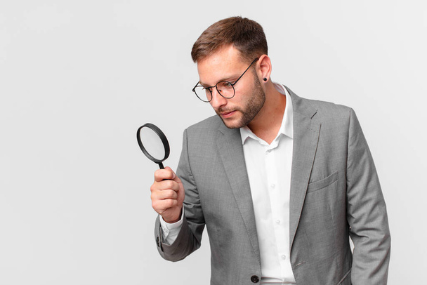 handsome businessman finfing with a magnifying glass - 写真・画像