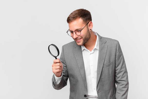 handsome businessman finfing with a magnifying glass - 写真・画像