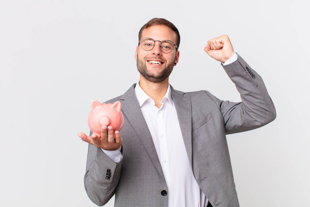 handsome businessman holding a piggy bank. savings concept - Foto, Imagem