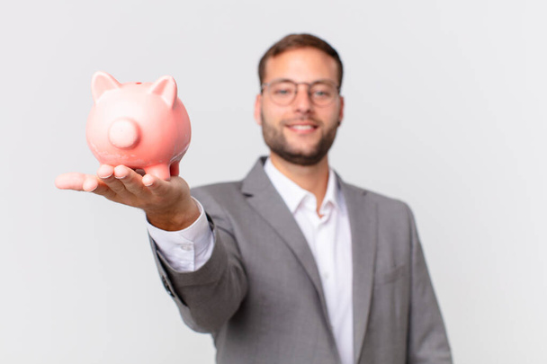 handsome businessman holding a piggy bank. savings concept - Fotó, kép