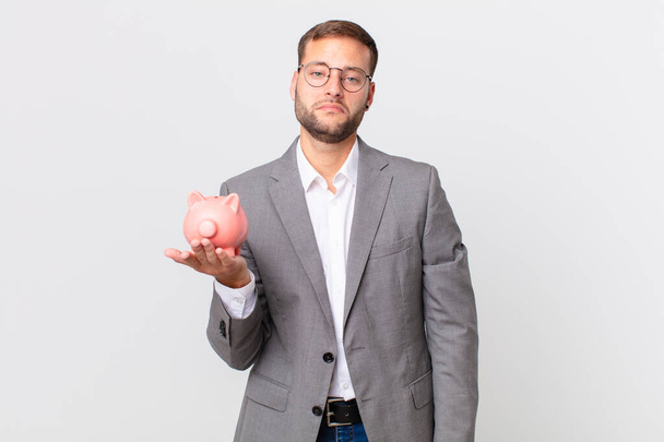 handsome businessman holding a piggy bank. savings concept - Foto, afbeelding