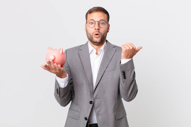 handsome businessman holding a piggy bank. savings concept - Foto, imagen