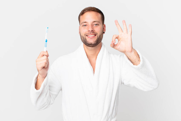 handsome man wearing bathrobe and holding a teeth brush - Foto, imagen