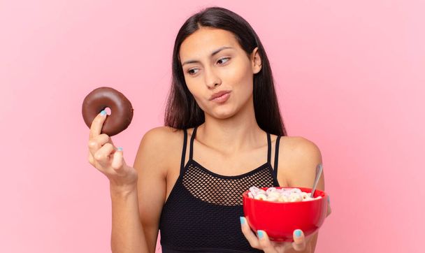 pretty fitness woman with a donut and a breakfast bowl - Фото, изображение