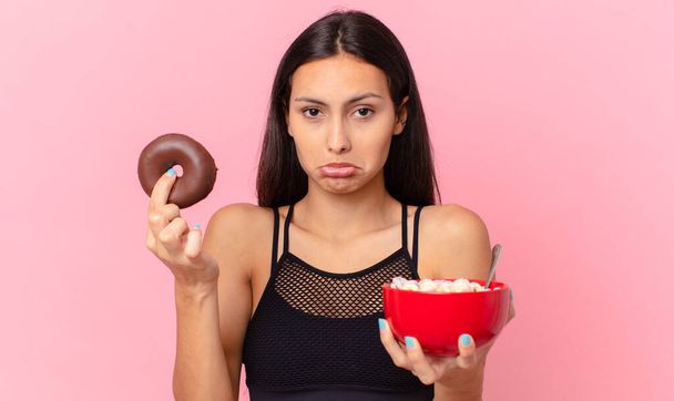 pretty fitness woman with a donut and a breakfast bowl - Fotó, kép