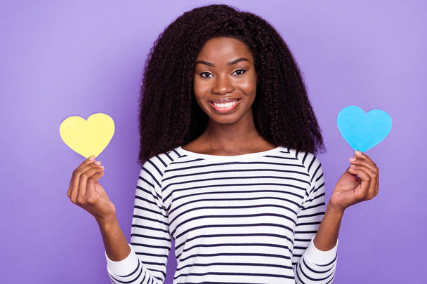 Photo of optimistic young lady hold hearts wear striped pullover isolated on violet color background - 写真・画像