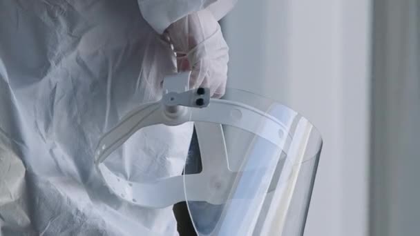 Felismerhetetlen orvos orvos orvos orvos nővér gyakorló tudós áll klinika laboratóriumi kórház ablakban visel fehér egyenruhát és latex kesztyű tartja a kezében átlátszó védő arcvédő pajzs - Felvétel, videó