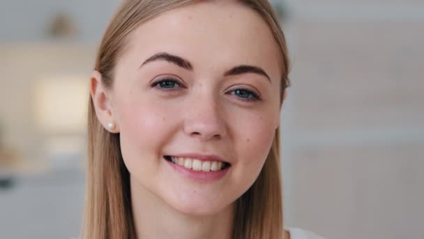 Cheerful pretty millennial single woman looking smiling at camera in living room indoors. Happy young adult beautiful lady with attractive face closeup portrait. White healthy teeth, dentistry concept - Video, Çekim
