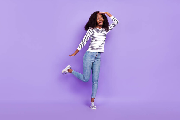 Full length photo of curious young lady look empty space wear striped pullover jeans isolated on violet color background - Valokuva, kuva