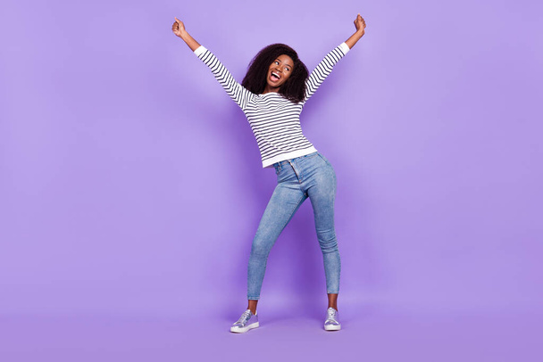Full body photo of nice hooray young lady look empty space wear striped pullover jeans isolated on violet color background - Photo, Image