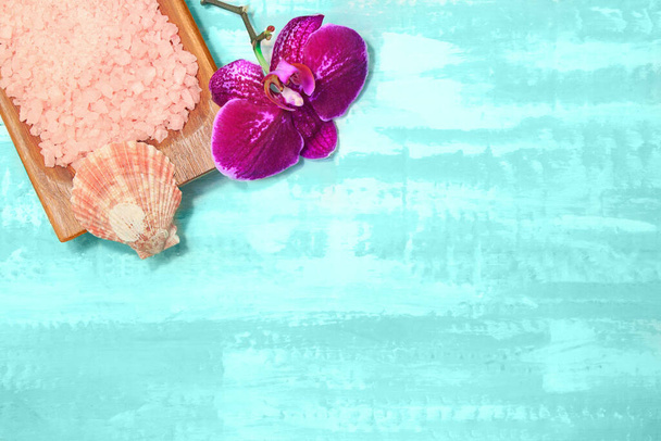 Holzschale mit rosa Meersalz mit Muschel und lila Orchidee. Beauty und Spa. Türkiser Hintergrund. Kopierraum - Foto, Bild
