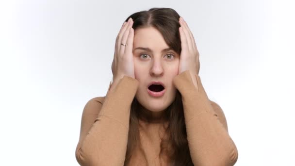衝撃的でストレスのかかる女性は口を開けて手で頭を保持します。衝撃と負の感情 - 映像、動画