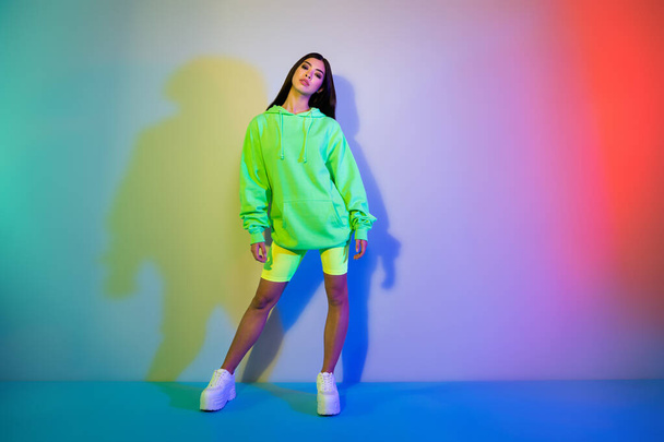 Full length body size view of attractive cool girl wearing sporty clothes posing isolated over multicolor vivid neon light background - Фото, зображення