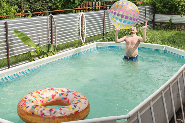 homem caucasiano jovem que se diverte na piscina, jogando com bola inflável colorida - Foto, Imagem