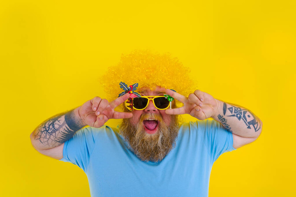 Fat man with wig in head and sunglasses dances - Photo, Image