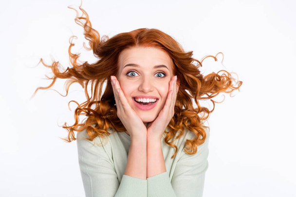 Photo portrait of red haired girl amazed touching cheeks with flying hair smiling isolated white color background - Foto, Imagen